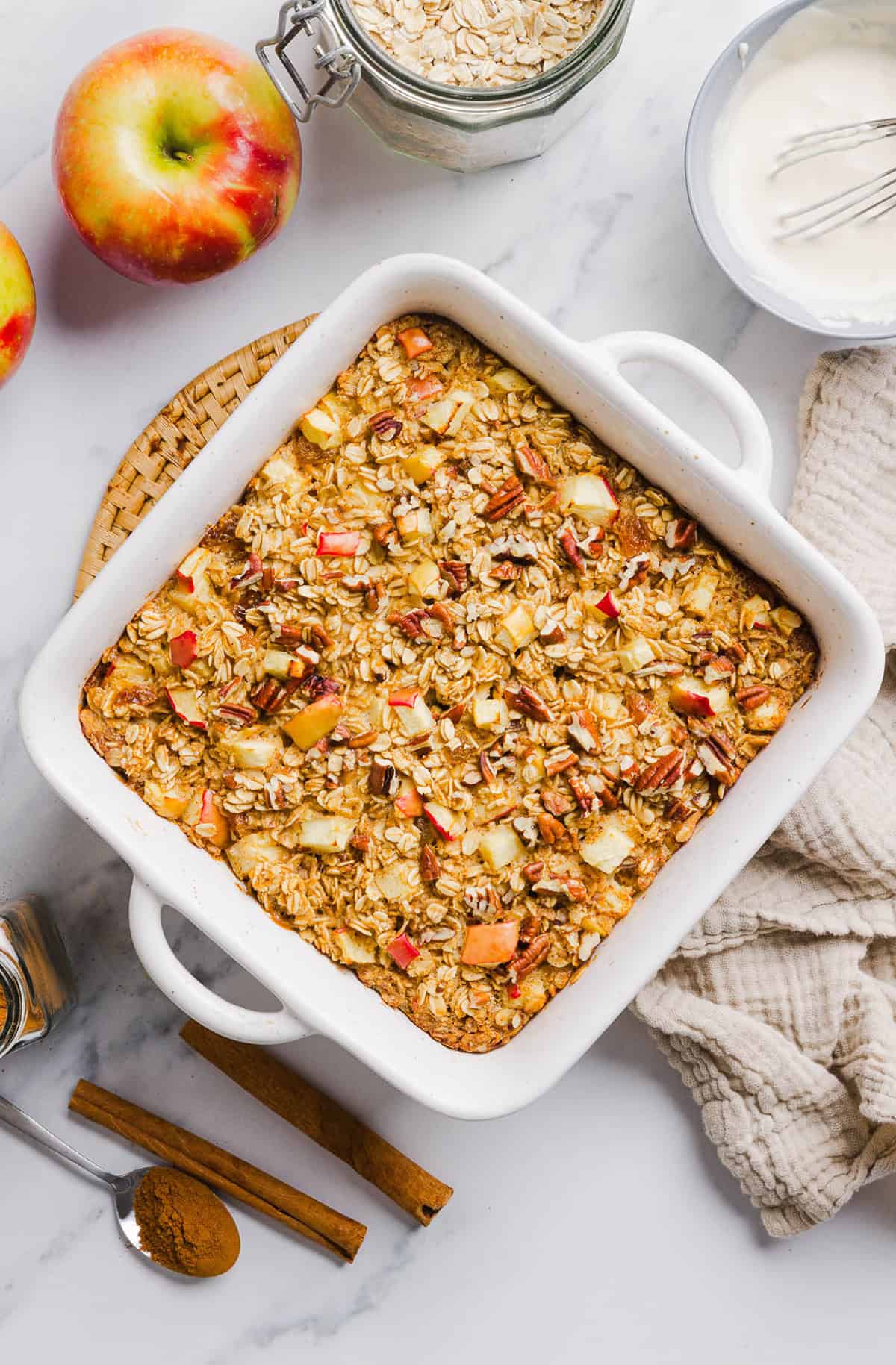 This Apple Cinnamon Baked Oatmeal is a cozy breakfast made with wholesome oats, shredded apples, and warm spices while naturally sweetened with maple syrup and plump raisins!  We also topped this with crunchy pecans and a delicious maple cream cheese glaze!