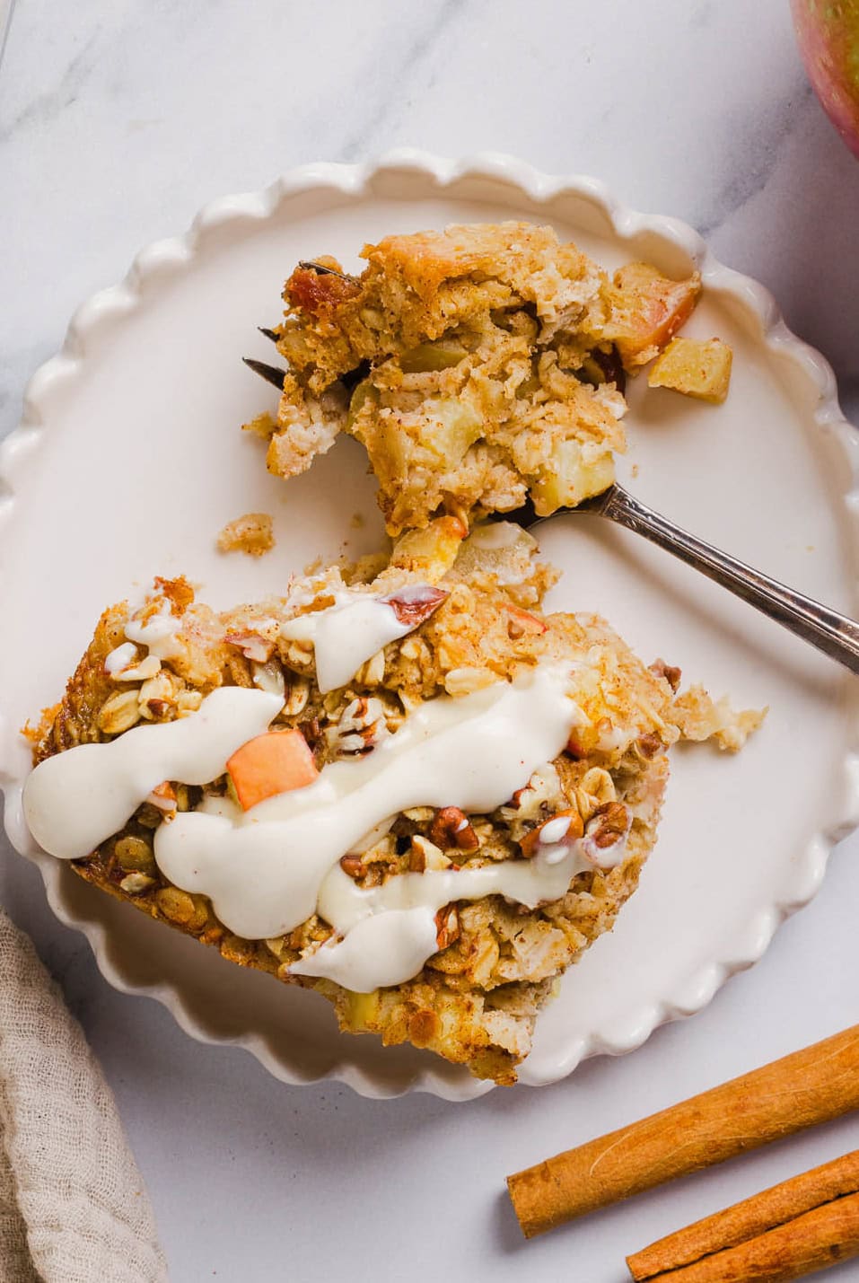 This Apple Cinnamon Baked Oatmeal is a cozy breakfast made with wholesome oats, shredded apples, and warm spices while naturally sweetened with maple syrup and plump raisins!  We also topped this with crunchy pecans and a delicious maple cream cheese glaze!